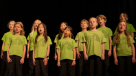 Group of children wearing shirts with the words Yarra Choir mid-performance