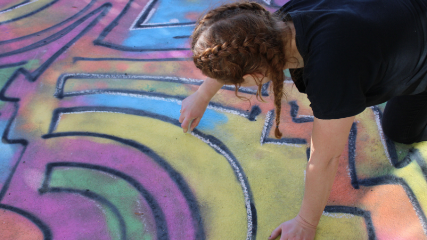 Child drawing a chalk artwork on the pavement