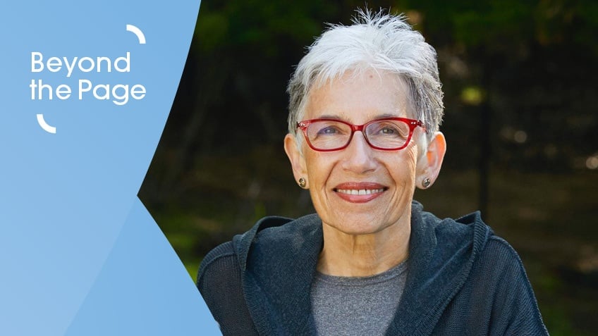 Old woman with short cropped hair and bright red glasses smiling at camera