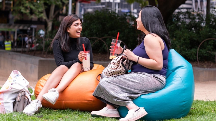 Two young people on beanbags mid-conversation and smiling