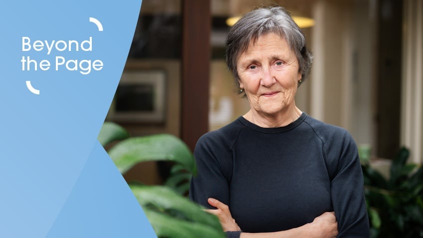 Older woman with cropped hair and dark shirt looking at camera