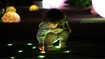 Small child crouching down to press light up buttons on ground