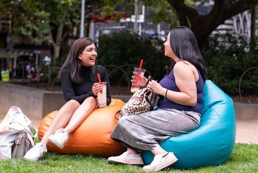 Two young people on beanbags mid-conversation and smiling