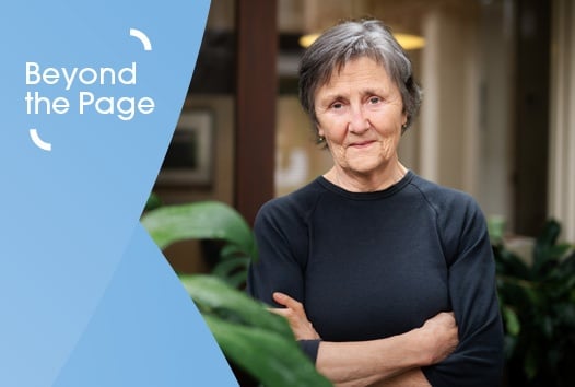 Older woman with cropped hair and dark shirt looking at camera